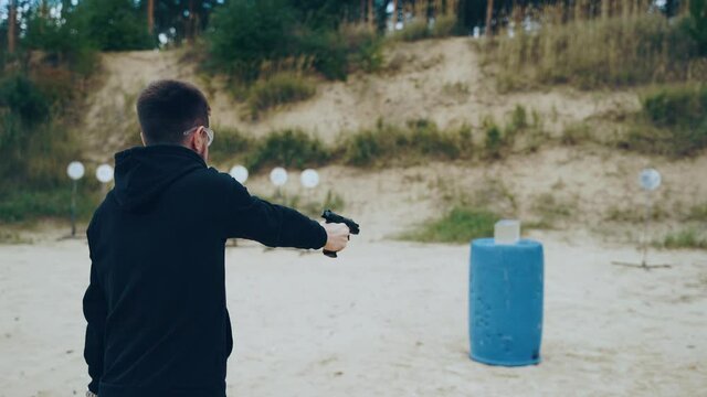 Shooting from a pistol at a ballistic gel on the street in a shooting club, a view from behind