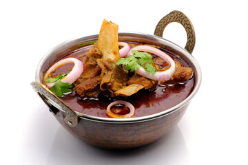 Indian style mutton curry in a copper brass bowl on white background