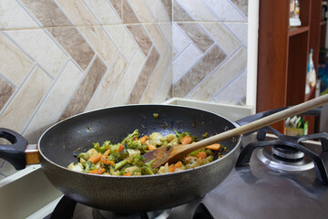 frying pan with vegetables and wooden spoon