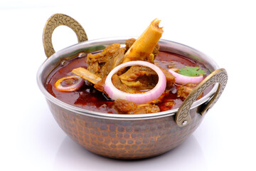 Indian style mutton curry in a copper brass bowl on white background