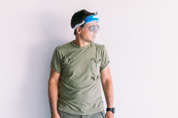 Military man with camouflage cap and sunglasses, with an antivirus protective screen, on a white wall