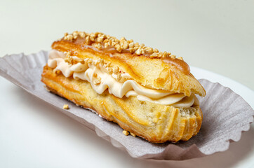 Eclair with cream and strawberries. On a white plate High quality photo