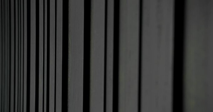 Black wood wall of different sizes it moves slowly, filmed from perspective. Modern real apartment with sliding door, beautiful furniture. Minimalist black and white design interior