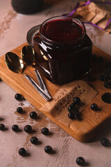 Glass jar with black currant jam in dark rustic kitchen
