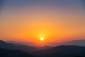 Bright summer sunset over the mountais silhouette.  