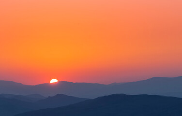 Bright summer sunset over the mountais silhouette.  