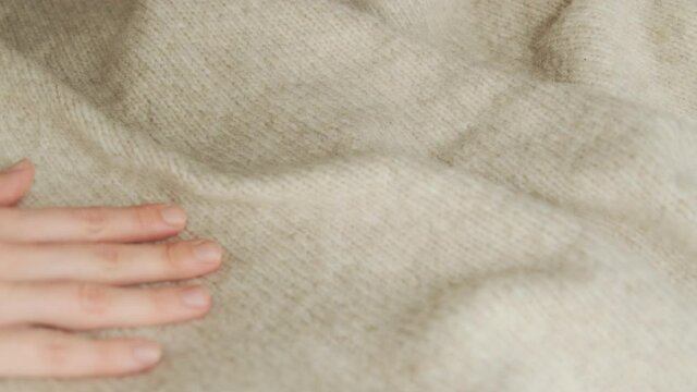Hand stroking over the surface knitted wool cloth or warm fluffy sweater. Handcraft knitting woolen fabric. 