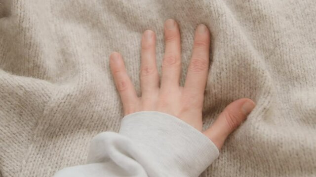Hand touching knitted wool cloth or warm fluffy sweater. Handcraft knitting woolen fabric surface. 