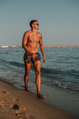 Handsome muscular man walking out of the water on a turquoise water beach.