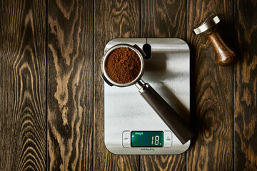 Accurate scale and portafilter with ground coffee, espresso recipe concept, wooden background with...