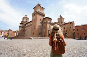 Travel in Italy. Rear view of traveler girl walking towards Este Castle (Castello Estense) of Ferrara, Italy. - obrazy, fototapety, plakaty