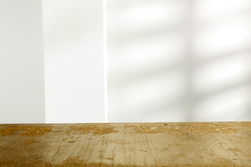 Golden table and white wall with morning sun shadows 