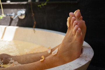 Funny male feet with rose petal popping out of tub