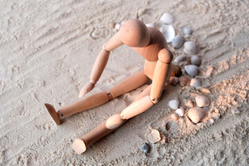The wooden dummy is resting, tired on the sand in the setting sun. Problems of modern man symbol