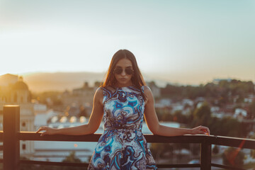 Close up image of happy brunette woman in sunglasses and summer clothes posing sideways outdoors