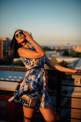 Close up image of happy brunette woman in sunglasses and summer clothes posing sideways outdoors