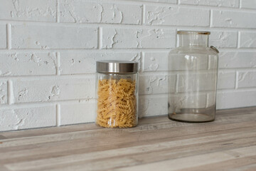 Wooden kitchen room. Macaroni in glass jars on shelf on kitchen wall. Cookware concept, kitchenware