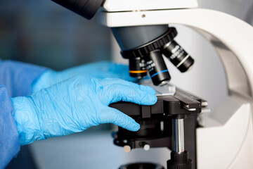Young female scientist looking at samples under the microscope