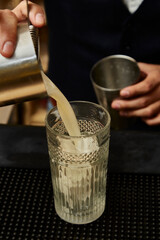 Long drink, sweet yellow transparent and white drink with pineapple decoration. Preparation of a drink with white drink, alcohol, liquor. Bartender's hands.