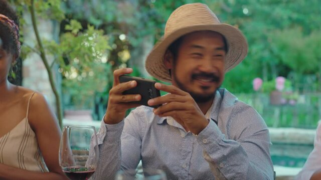 cool asian man taking photo with friend using smartphone best friends at dinner party enjoying summer celebration sharing vacation memories on social media 4k
