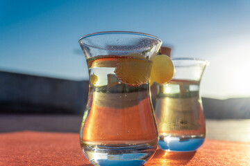 Detail of ripe grapes adorning the rim of some crystal glasses with cava or champagne, illuminated with direct sunlight at sunset.