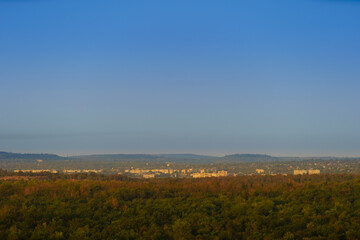 Obraz premium Panoramic view of a small town in eastern Europe in the morning or evening light, the city is surrounded by hills and forests.