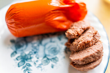 Packaged storebought cooked sliced Liver sausage in plastic packaging on plate for snack on toast...