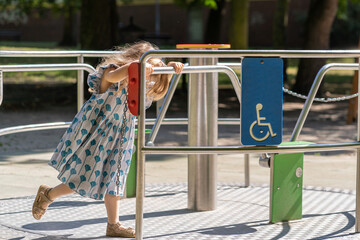 A girl playing on a merry-go-round for the disabled.