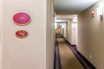 Closeup of sign at inn hotel motel with number for non-smoking room and empty corridor at night