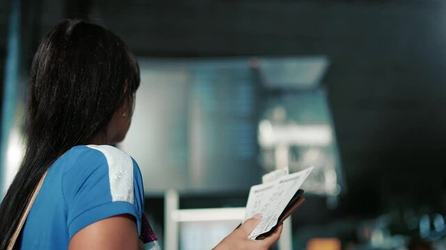 Female tourist waiting boarding checking time flight information on arrival departure board airport
