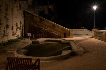 Night scene on ornamental stone basin, stairs in the background leading to the city center