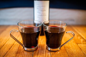Closeup of two glasses of alcohol red wine cabernet sauvignon or merlot and bottle in background