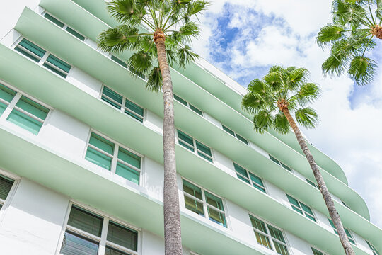 Miami Beach, Florida colorful pastel green house apartment building with Art Deco district style architecture looking up on palm trees and windows