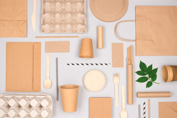 Different eco-friendly tableware and kraft paper food packaging on gray background. Street food paper packaging - cups, plates, straws, containers and paper bags. Mockup, flat lay. Selective focus