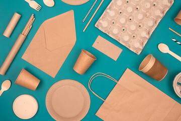 Flat lay with eco-friendly tableware and sustainable packaging. Kraft paper food packaging on green...