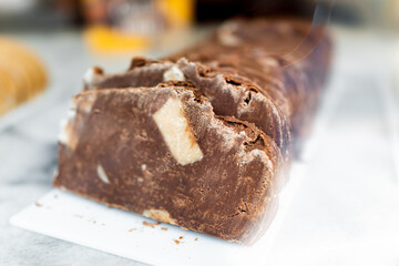 Macro closeup of milk or dark chocolate homemade fudge slices in candy dessert store at retail display with pieces of white cacao