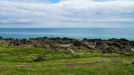 Scenic view of a rocky coast against a refreshing blue ocean © Robert Mccabe/Wirestock