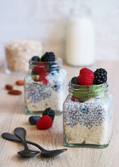 Obraz na płótnie Canvas Healthy overnight oatmeal and chia seed pudding with milk and red berries fruit in a jar on wooden table 