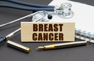 On the table is a notebook, a stethoscope and a sign with the inscription - BREAST CANCER