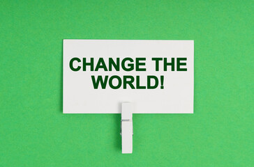 On a green background, a business card on a clothespin. The business card says - Change The World