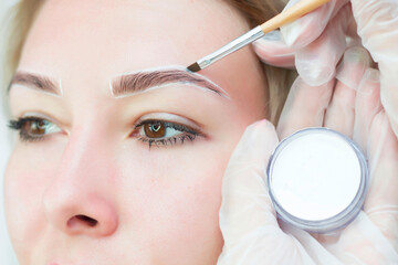 Make-up artist makes markings with white pencil for eyebrow and paints eyebrows. Professional...