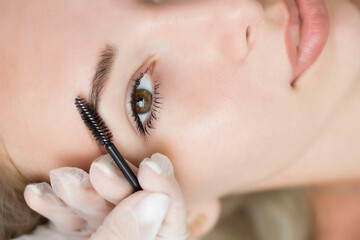 The girl, smiling, combs her eyebrows, raised one eyebrow. The concept of eyebrow design.
