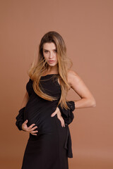 Beautiful pregnant young woman in studio on beige background