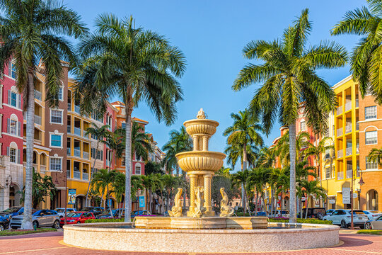 Naples, USA - July 24, 2021: Bayfront residential street condos condominiums colorful multicolored buildings with water fountain by palm trees and blue sky