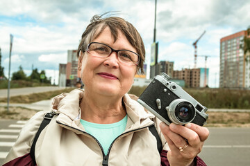 Grandmother with a camera. An elderly woman with a camera walks around the city.