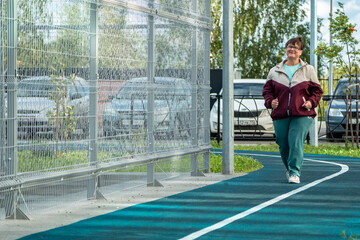 Grandma goes in for sports. An elderly woman runs on the sports ground.