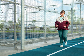 Grandma goes in for sports. An elderly woman runs on the sports ground.