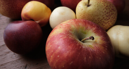 Juicy fruits on a old wooden table. Apples, pears, plums, apricots, close up