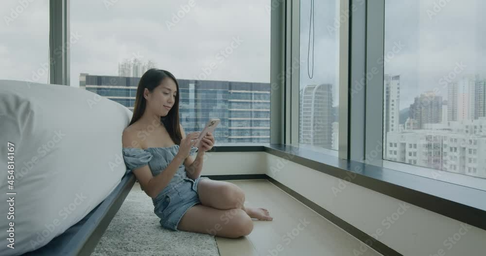 Wall mural woman use of mobile phone and sit beside the bed