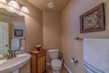 Interior of a small bathroom with pedestal sink and woven floor cabinet